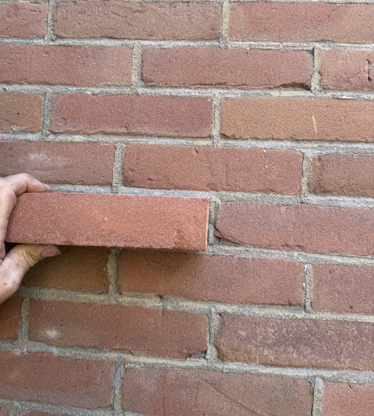 Oranjerode baksteenmatch tegen een bestaande gevel