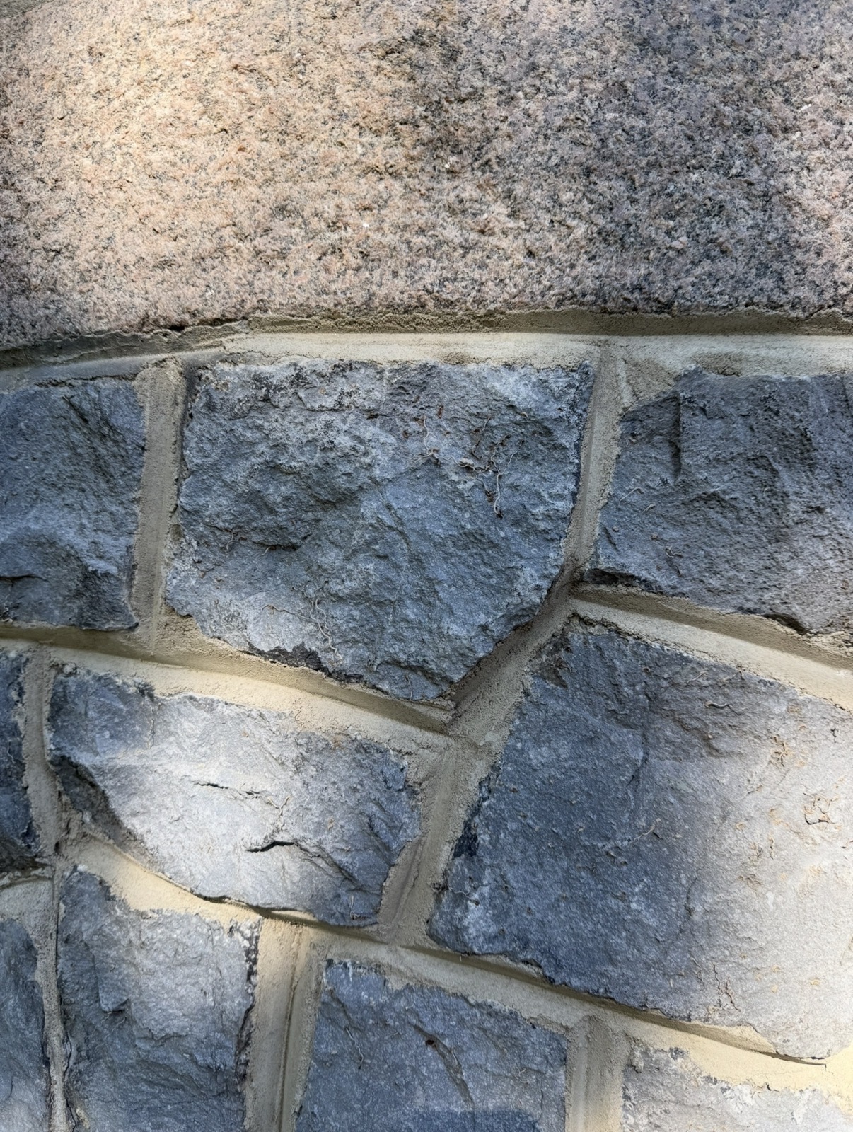 Herstelde aansluiting tussen basalt parementwerk en de granieten gevelplint