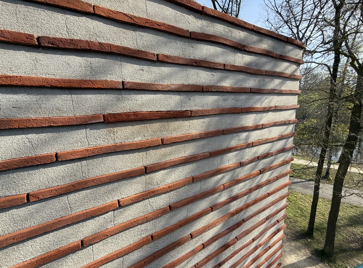 Rustig gevelvlak met doorlopende rode baksteenbanden na herstel